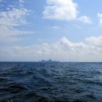 Cleveland from about 10-12 miles out. <br><br><i>
During a late-night Bourbon fueled conversation back in 2014, I told Lawrence about the GLSS and he was interested. The GLSS doesn’t make it easy to try one of the challenges. Besides all the safety gear, they require non-members to submit a sailing resume that must be approved by their board. One of the requirements that must be on the resume is a well-documented “Qualifying Sail.” This consists of a sail that must be over 24 hours long and over 100 statute miles. </i>